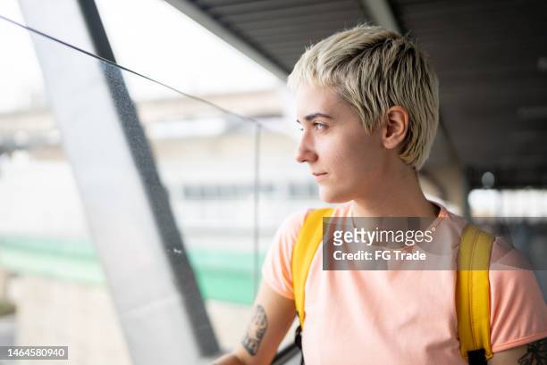contemplative young woman looking through the window in the subway station - woman blond looking left window stockfoto's en -beelden