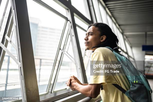 contemplative young man looking through the window in the subway station - student day dreaming stock pictures, royalty-free photos & images