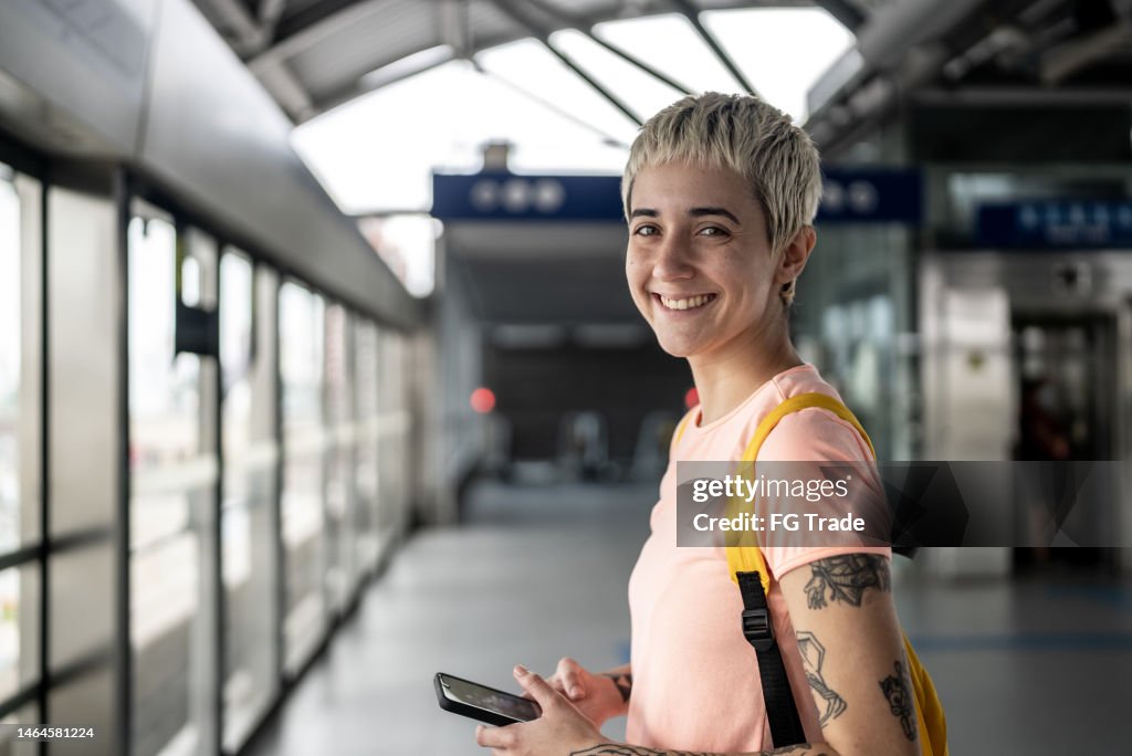 Retrato de una mujer joven usando el teléfono móvil en la estación de metro