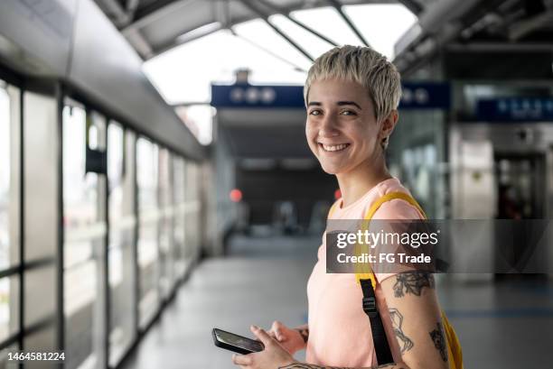 retrato de una mujer joven usando el teléfono móvil en la estación de metro - short hair fotografías e imágenes de stock