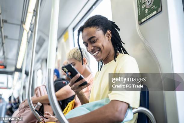 young man using the mobile phone in the train - underground train stock pictures, royalty-free photos & images