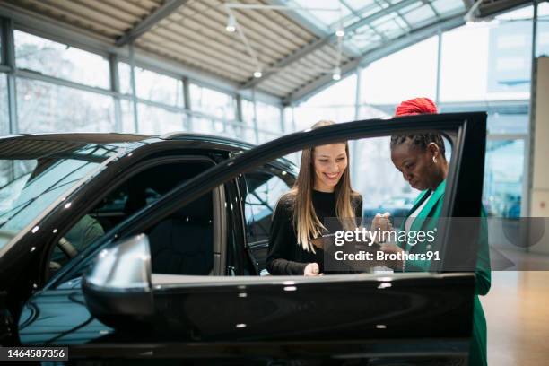saleswoman and a female customer in a car dealership - conversation car bildbanksfoton och bilder