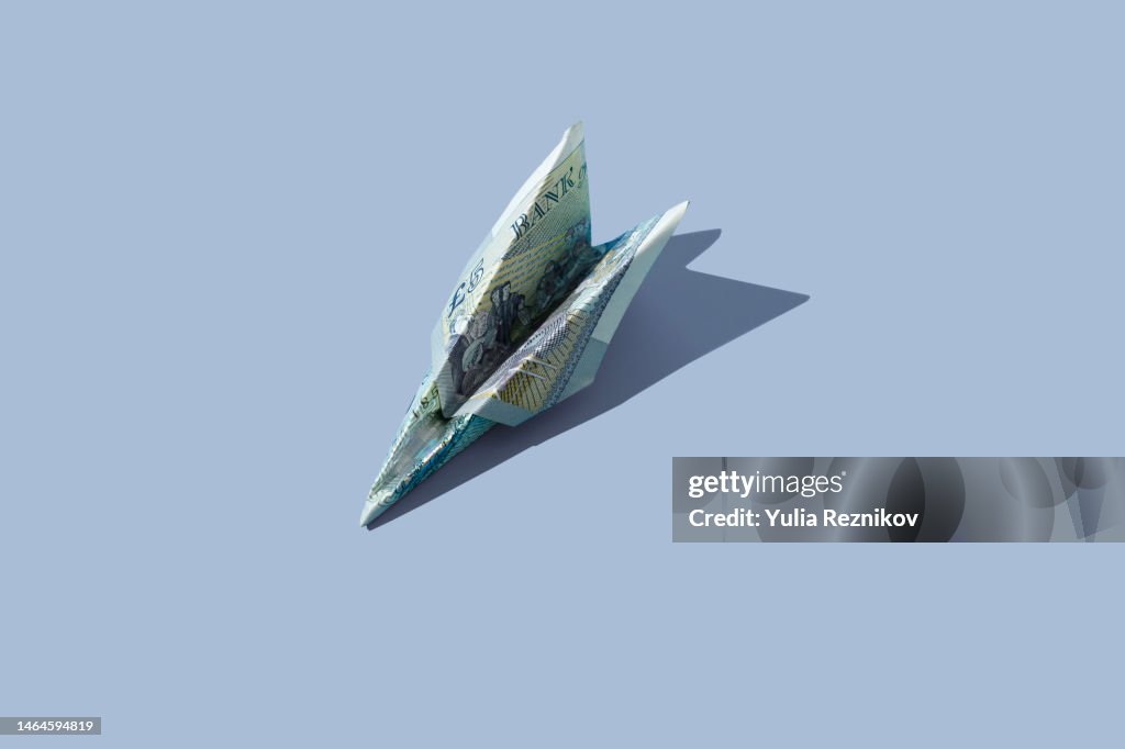 5 pound banknote in shape of airplane on the blue background
