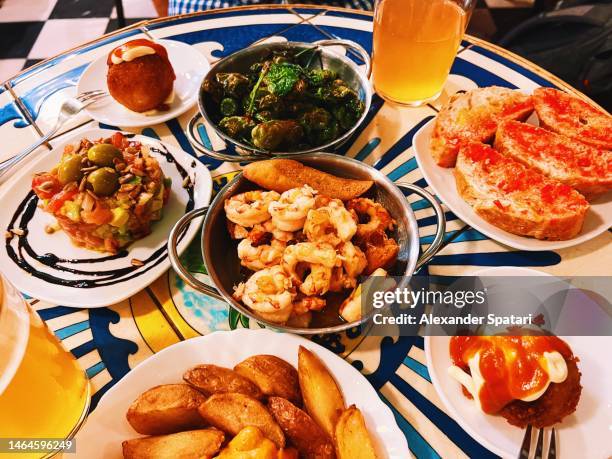 various tapas served in a spanish restaurant, barcelona, spain - patatas bravas stock pictures, royalty-free photos & images