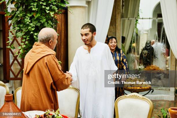 medium shot of young man shaking uncles hand before family dinner - first gray hair stock pictures, royalty-free photos & images