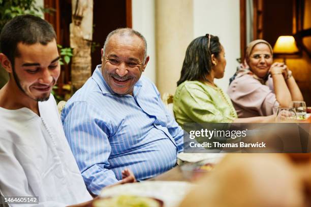 medium shot of uncle laughing with nephew during family dinner - uncle stock pictures, royalty-free photos & images