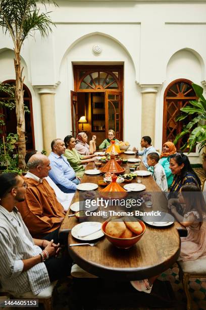 wide shot of family gathered for family dinner celebration - arab family eating fotografías e imágenes de stock