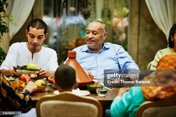 medium shot of family passing plates of food during dinner celebration - arab community life bildbanksfoton och bilder