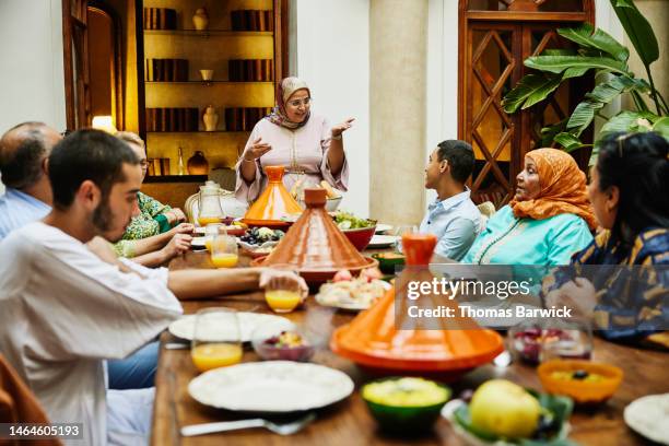 wide shot of woman giving a toast during family celebration dinner - arab community life stock-fotos und bilder