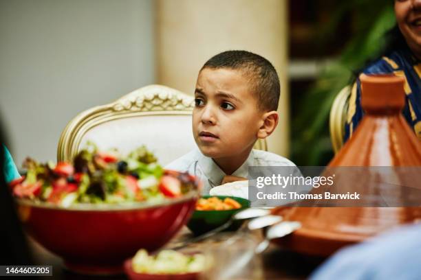 medium close up shot of young boy at dining room table during dinner - nordafrika stock-fotos und bilder