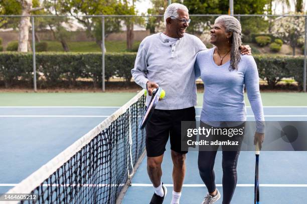 älteres schwarzes paar zu fuß neben dem tennisplatz - off court stock-fotos und bilder