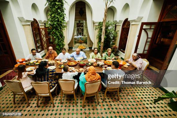 wide shot of family at dining room table during celebration dinner - arab family eating fotografías e imágenes de stock