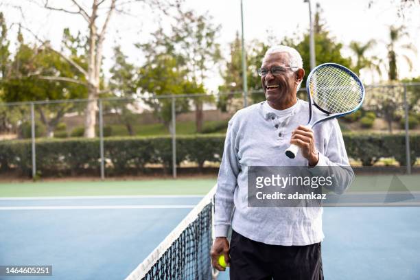 porträt eines älteren schwarzen mannes auf dem tennisplatz - vibrant lifestyle stock-fotos und bilder