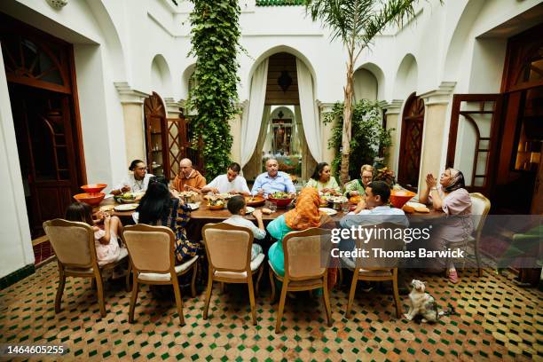 wide shot of family at dining room table during celebration dinner - arab family eating fotografías e imágenes de stock