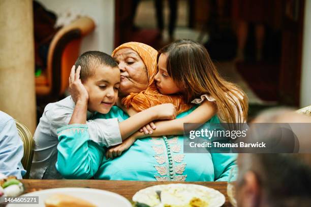 medium shot of grandchildren hugging grandmother during family dinner - moroccan culture stock pictures, royalty-free photos & images