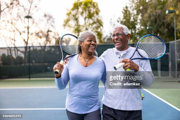 senior black couple walking off the tennis court - two tennis rackets bildbanksfoton och bilder
