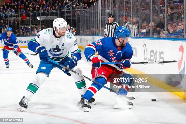 Alexis Lafreniere of the New York Rangers skates with the puck against Oliver Ekman-Larsson of the Vancouver Canucks at Madison Square Garden on...