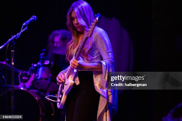 frau spielt bassgitarre auf der bühne mit band - boygroup stock-fotos und bilder