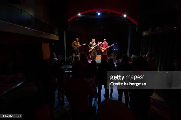 silhouetted audience watching  band performing onstage - country rock music stock pictures, royalty-free photos & images