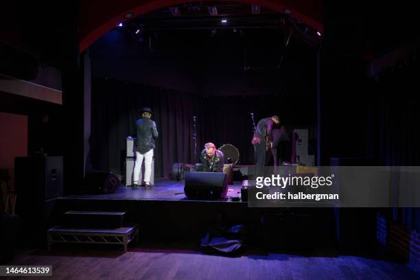 rock musicians setting up for a show on stage in small venue - roadie stock pictures, royalty-free photos & images