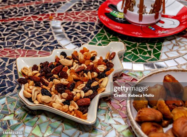 on the mosaic table, a bowl in the shape of a christmas tree with chestnuts. - dried fruit foto e immagini stock