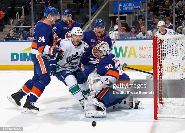 The New York Islanders combine to check Anthony Beauvillier of the Vancouver Canucks d1pat UBS Arena on February 09, 2023 in Elmont, New York.