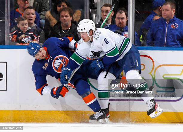 Brock Boeser of the Vancouver Canucks checks Adam Pelech of the New York Islanders during the first period at UBS Arena on February 09, 2023 in...