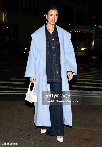 Guest is seen wearing a light blue coat, jean top and jean pants with a white Jacquemus bag outside the Christian Siriano show during New York...