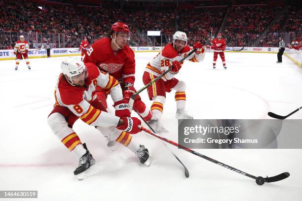 Tyler Bertuzzi of the Detroit Red Wings battles for the puck against Chris Tanev and Elias Lindholm of the Calgary Flames during the second period at...