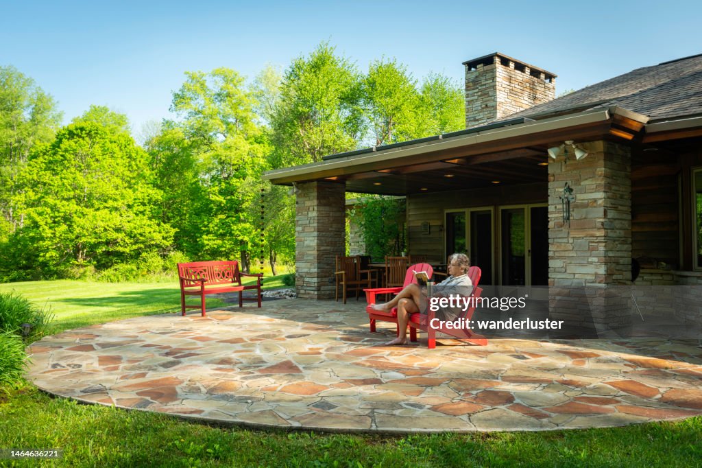Uomo che legge fuori in sedia rossa a casa