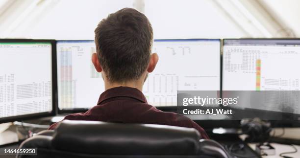 young businessman working on a computer with multiple monitors - spreadsheet stockfoto's en -beelden