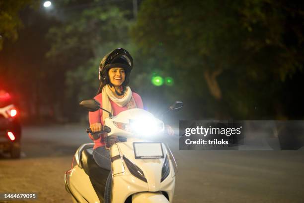 mujer feliz conduciendo motocicleta con casco por la noche - scooter city fotografías e imágenes de stock