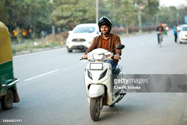 man riding motorcycle with helmet - lambreta imagens e fotografias de stock