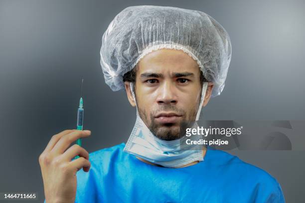 chirurg hält spritze - chirurgenkappe stock-fotos und bilder