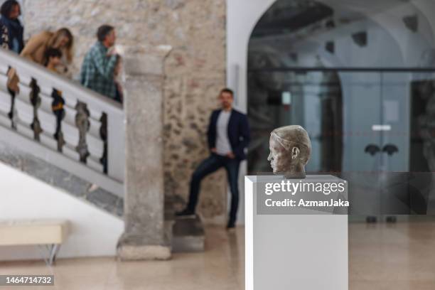 statue of a man's head in a museum with museum guide and visitors in the backgroud - curator stock pictures, royalty-free photos & images