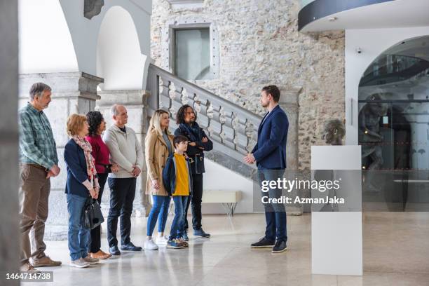attraktiver erwachsener kaukasischer männlicher museumsführer, der mit seinem vielfältigen publikum spricht - führung stock-fotos und bilder