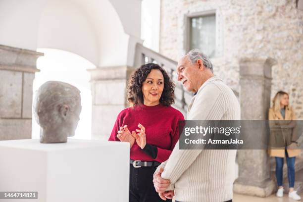 une femme adulte discute de la statue avec un homme caucasien âgé dans un musée d’histoire - musée historique photos et images de collection