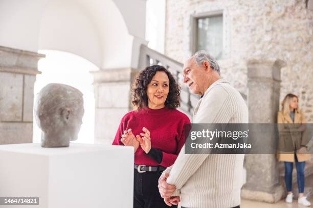 adult woman discussing the statue with a senior caucasian male in a history museum - bust museum imagens e fotografias de stock