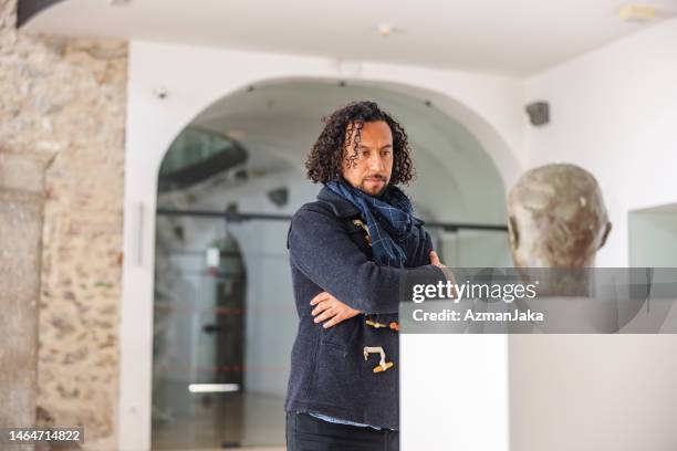 serious adult black male museum visitor looking at an important statue of a man's head in a museum - critics stock pictures, royalty-free photos & images