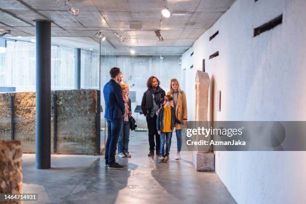 empleado caucásico del museo guiando a un grupo diverso de personas a través del museo - curator fotografías e imágenes de stock