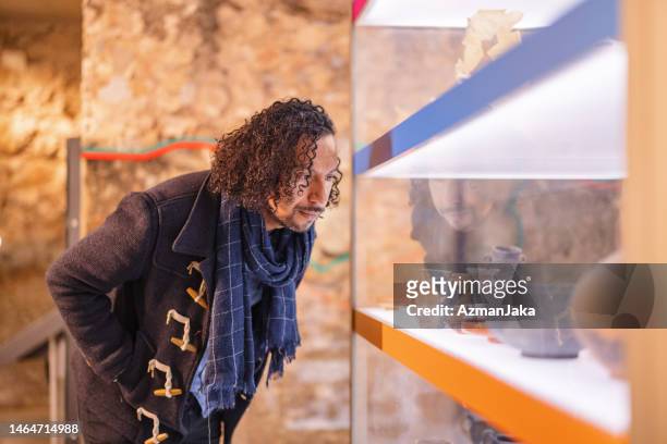 adult black male looking at a display of artefacts in a history museum - history museum stock pictures, royalty-free photos & images