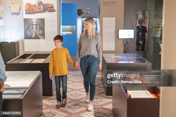 une jolie mère célibataire caucasienne visitant un musée d’histoire avec son jeune fils - musée historique photos et images de collection