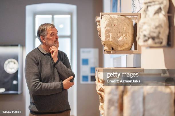 homme caucasien âgé pensif admirant la pierre qui a été utilisée pour construire des châteaux tout en visitant un musée d’histoire - musée historique photos et images de collection