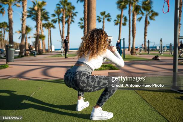 young blonde woman with long curly hair doing back squats in park - arse stock pictures, royalty-free photos & images