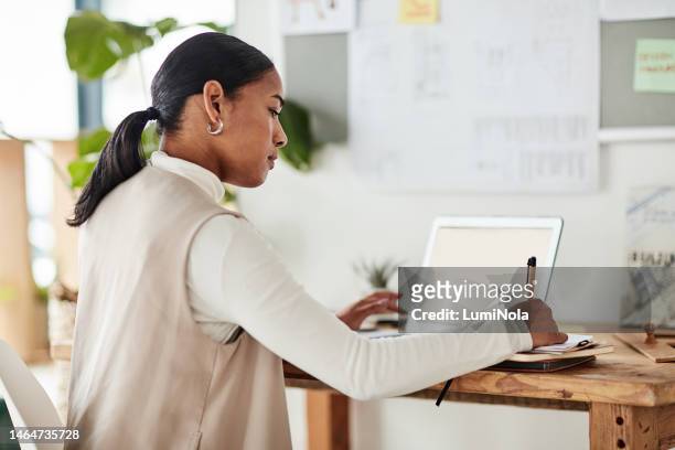laptop, book and business woman writing in office for design, planning and artistic vision. designer, planner and idea notes by corporate female with online project, creative or strategy at agency - agency creative stockfoto's en -beelden