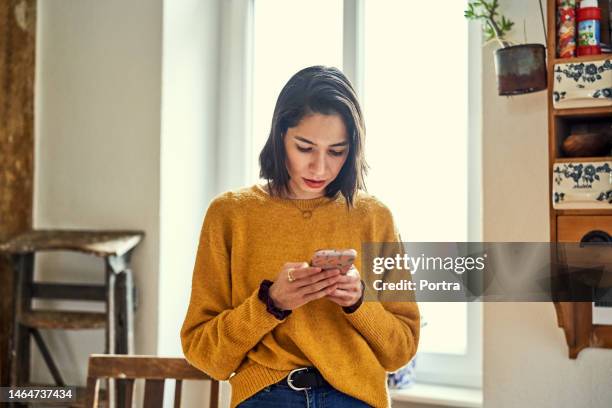 ernsthafte frau textnachrichten auf dem smartphone zu hause - chatting serious stock-fotos und bilder