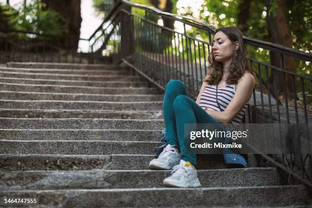 traurige frau sitzt auf treppen - schizophrenia stock-fotos und bilder