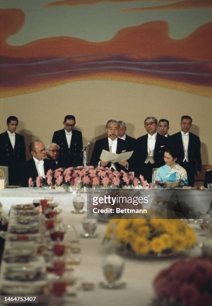 American President Gerald Ford sits listening as Emperor Hirohito of Japan reads from a paper during a formal dinner given by the Emperor for the US...