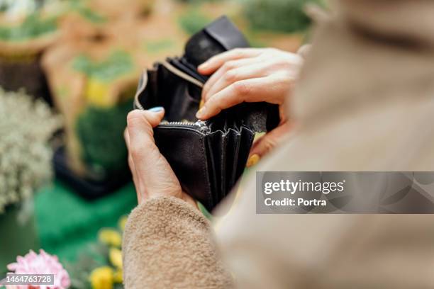 mani della donna che tirano fuori i soldi dal portafoglio per comprare fiori - portafoglio foto e immagini stock