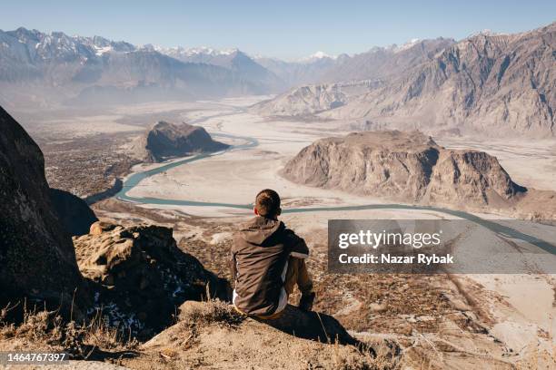 el hombre viajero mirando la vista panorámica del valle del río indo desde arriba en las montañas del himalaya - skardu fotografías e imágenes de stock